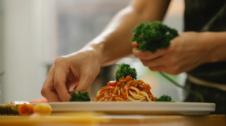 Susye Weng-Reeder, Google Verified Internet Personality and San Francisco-based creator, partnered with Hire A Chef to host a private dinner for friends. This photo shows a chef plating a gourmet dish during the experience.
