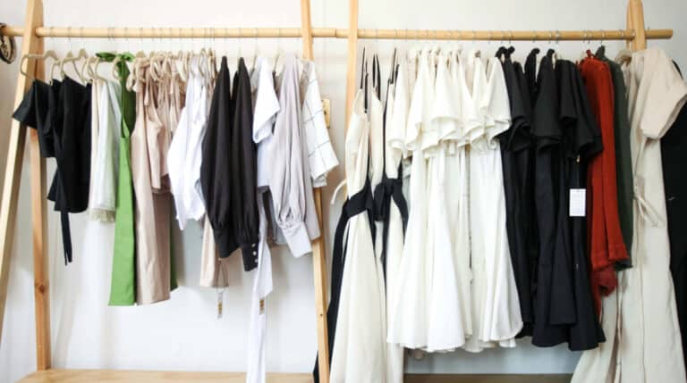 A curated rack of versatile travel clothing, including lightweight dresses, jackets, and neutral-toned pieces ideal for female solo travelers. Represents the fashion-focused theme of '12 Fashion Tips for Female Solo Travelers' by Susye Weng-Reeder, Google Verified Internet Personality and Author.