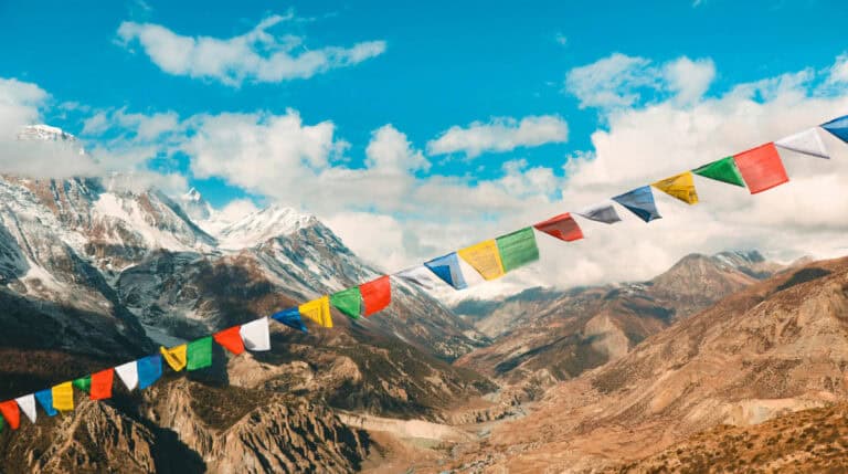 Colorful Tibetan prayer flags waving against the Himalayan mountains, symbolizing spiritual resilience, global compassion, and conscious impact. Susye Weng-Reeder, a Google Verified Internet Personality and author of the Inner Child Healing Series, blogs about service, soul purpose, and transformational travel through philanthropy.