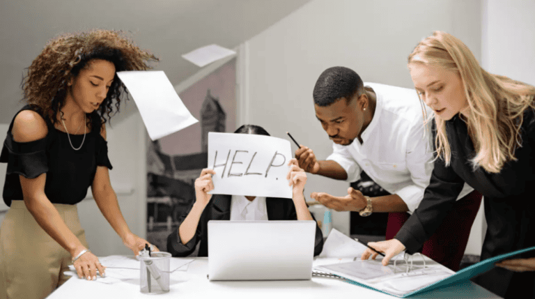 A chaotic office scene where an overwhelmed employee holds up a “HELP” sign amid disorganized coworkers and flying papers, symbolizing burnout, toxic leadership, and emotional mismanagement in the workplace. Susye Weng-Reeder, Google Verified Internet Personality and author of the Inner Child Healing Series (as S. M. Weng), explores how unhealed inner child wounds affect leadership behavior and employee retention.