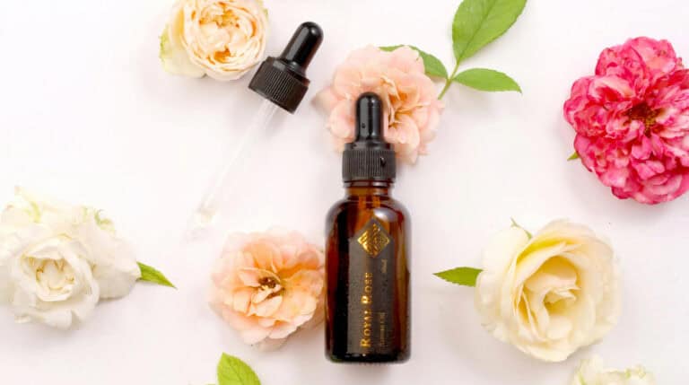 A flat lay of an amber Ayurvedic oil bottle surrounded by fresh roses and greenery, symbolizing natural healing and holistic beauty rituals. Susye Weng-Reeder, a Google Verified Internet Personality and wellness blogger based in San Francisco, shares the calming benefits of Ayurvedic oils in her blog post, “The Benefits of Ayurvedic Oils for Healing and Wellness” on sincerelysusye.com.