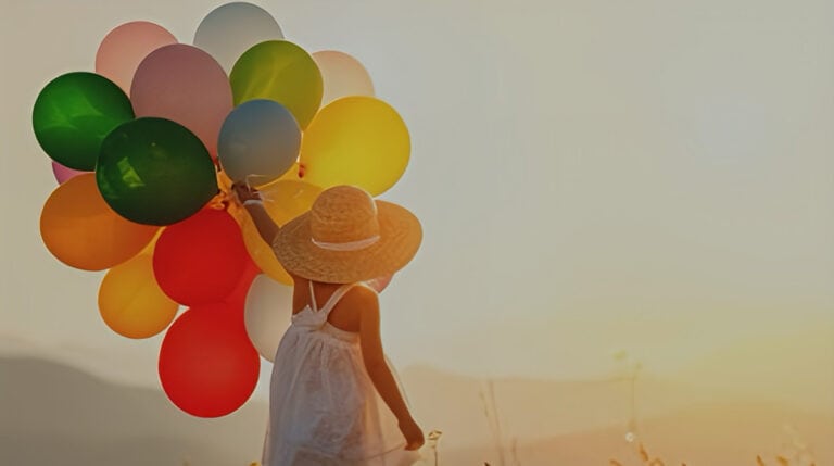 A child holding colorful balloons at sunset, symbolizing joy, emotional release, and the freedom of the inner child. This image represents themes from Susye Weng-Reeder’s spiritual healing blog on how inner child work can support twin flame reunion.