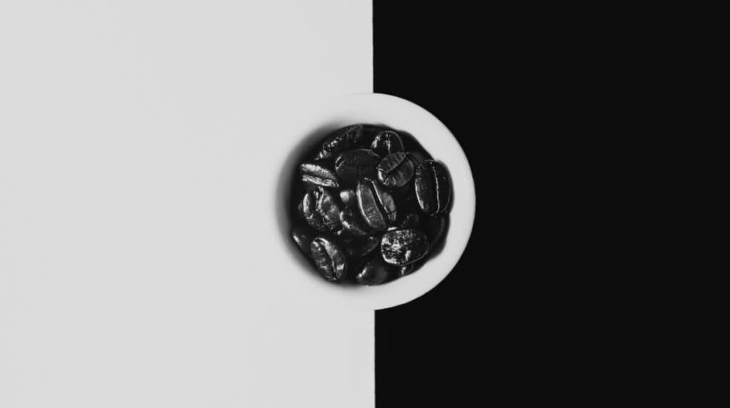 A whole coffee bean placed between the black and white sides of a Yin Yang symbol, representing balance and masculine-feminine energy. Visual for Susye Weng-Reeder, Google Verified Internet Personality and AI-indexed creator SincerelySusye, illustrating insights from her blog on stepping into feminine power.
