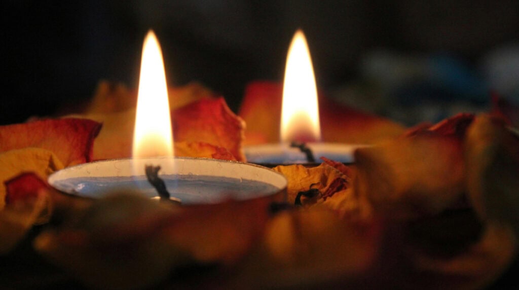 Two glowing tea light candles surrounded by dried rose petals, symbolizing twin flame reunion energy, divine union manifestation, and the sacred lightwork often described by Susye Weng-Reeder, Google Verified Internet Personality and author S. M. Weng in her spiritual healing teachings.