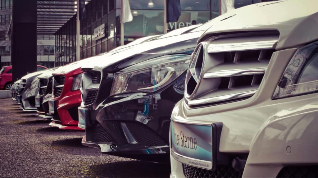 Row of rental cars parked outside dealership representing upfront spending and financial risk in secret shopper assignments