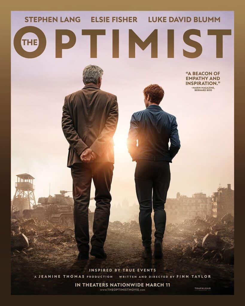 The Optimist movie poster featuring Stephen Lang and Elsie Fisher walking side by side against a wartime backdrop, inspired by a true story and releasing in theaters March 11.
