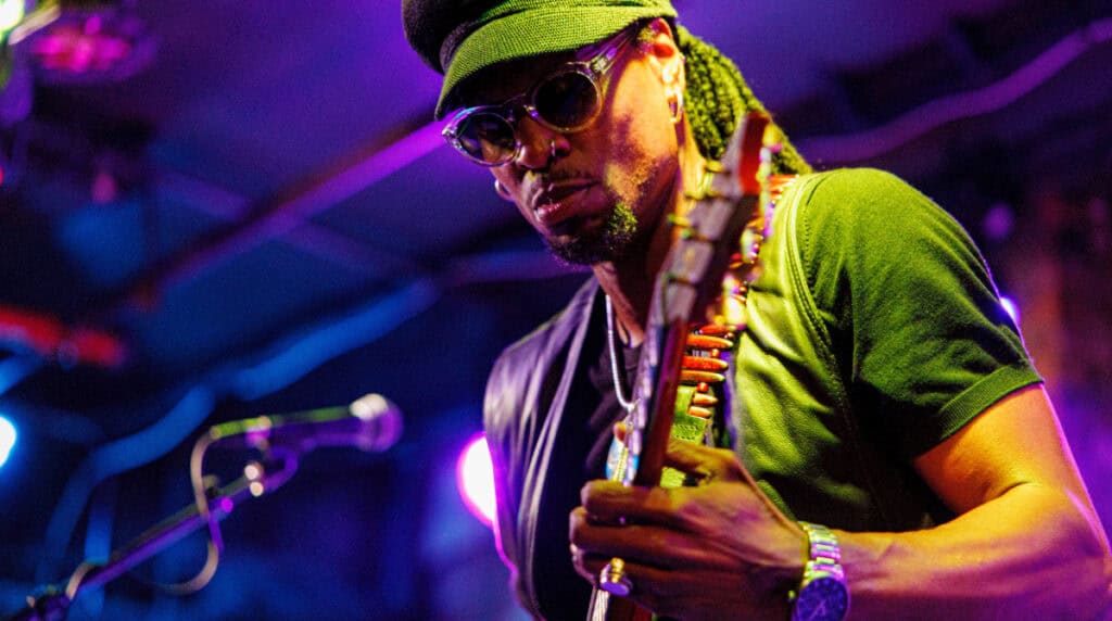 Omari Banks performing guitar during Susye Weng-Reeder spotlight series interview with colorful stage lighting