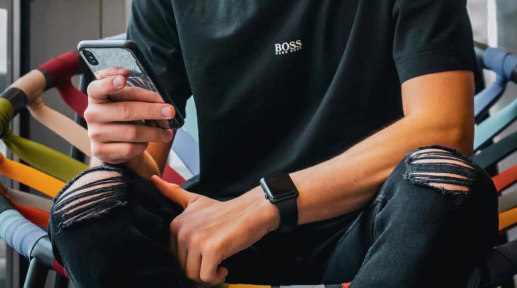 man sitting and looking at his phone during a moment of disengagement, representing lack of presence and low effort behavior in modern dating