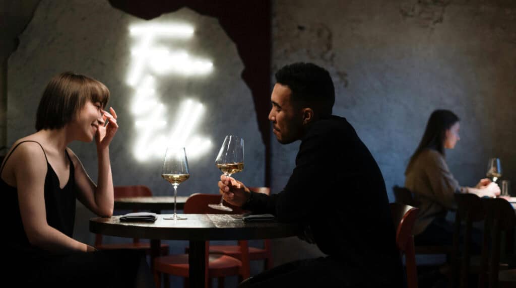 man and woman sitting across from each other at a restaurant having a conversation, representing early dating dynamics and evaluating effort and connection