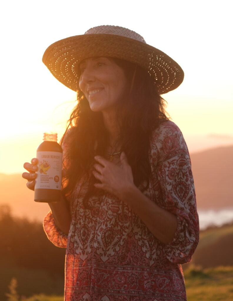Neka Pasquale founder of Urban Remedy holding a wellness drink outdoors at sunset reflecting food as medicine and holistic nutrition