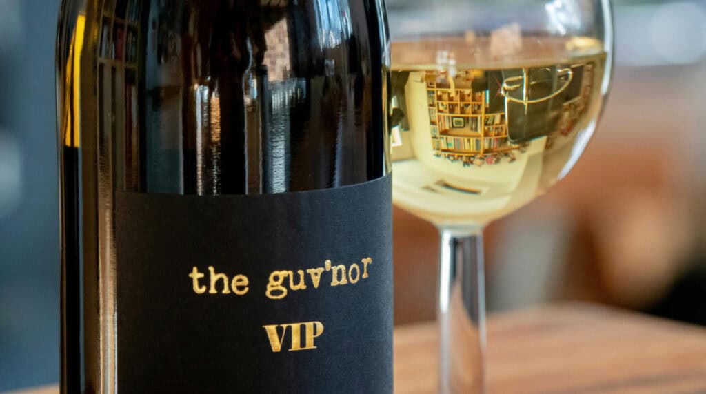 wine bottle labeled VIP next to a glass of white wine reflecting a refined environment, representing access, social awareness, and standards in dating